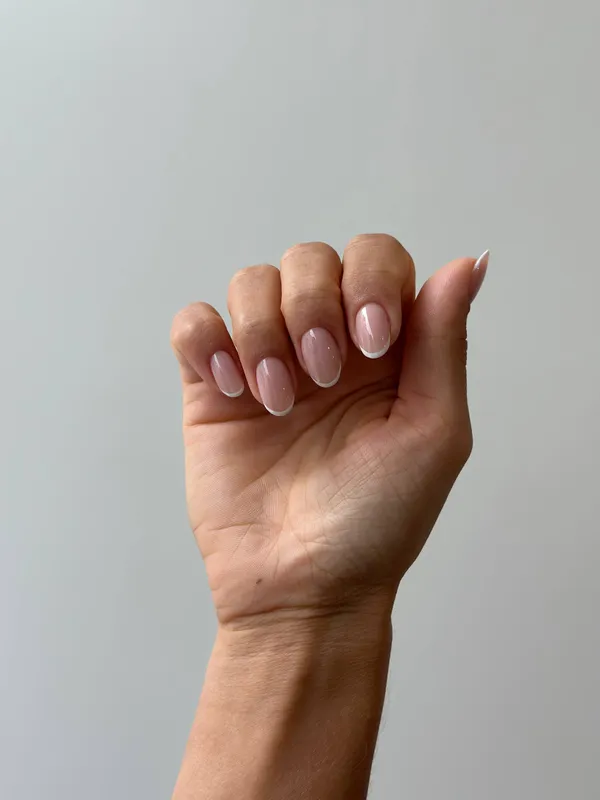 Short almond nails in sheer pink with thin white French tips