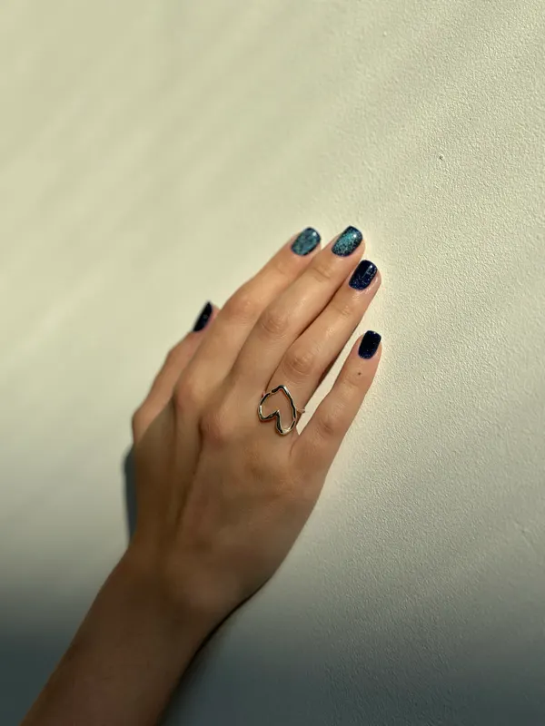 Short nails in deep navy with a gold chevron ring